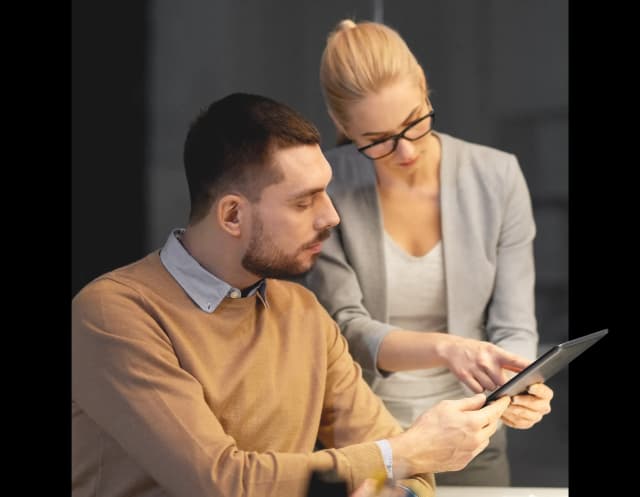 Mężczyzna i kobieta sprawdzają razem coś na tablecie.